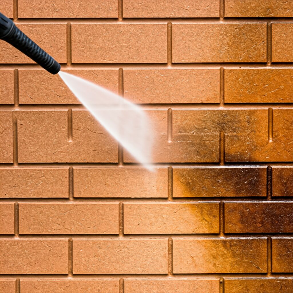 Brick wall being restored using high-pressure washing to remove grime and dirt.